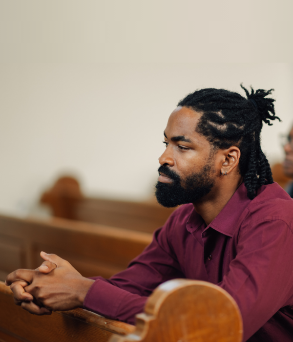 Connect deeper with your faith through Christian counseling. A man prays in church after finding clarity in Christian-based therapy.
